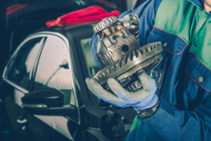 An auto mechanic fixing a vehicle differential.